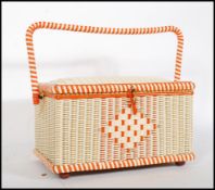 A vintage retro 20th Century sewing box having white and orange wicker body, hinged lid opening to