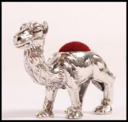 A small sterling silver pin cushion in the form of a camel having a red velvet cushion to the