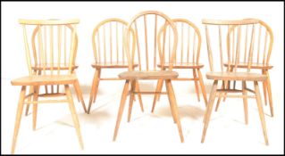 A harlequin set of mid century Ercol beech and elm wood dining chairs. Raised on turned legs