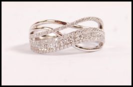 A stamped 18ct white gold cross over ring set with diamond accent stones. Weight 5.3g. Estimated