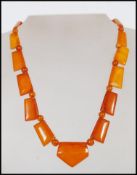 A vintage Art Deco amber bakelite necklace with yellow metal clasp. Large axe shaped panels with