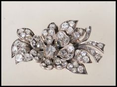 A mid 20th Century diamond flower brooch modelled with a central bloom having foliage behind, all
