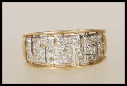 A hallmarked 9ct yellow gold ring having illusion pierced greek key decoration set with diamond