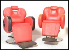 A pair of 20th Century red leatherette barbers chairs, scroll arms with adjustable headrests, raised