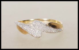A stamped 375 9ct gold ring having cross over design illusion set with white stones. Weight 1.7g.