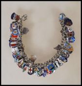 A vintage sterling silver souvenir / charm bracelet having a large number of silver enamelled
