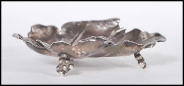 A sterling silver footed dish in the form of a grape leaf with embossed detailing raised on three