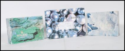 A group of three Rolex boxes each printed with a different design, two marked Oyster. Designs