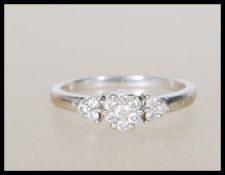 A hallmarked 9ct white gold ring set with a central cluster of white stones flanked by three further