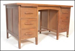 A mid century Air Ministry style oak twin pedestal desk raised on squared legs with a series of
