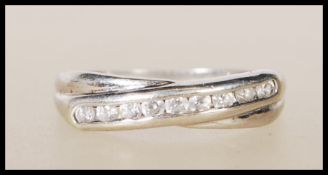A hallmarked 9ct white gold cross over ring set with with white accent stones. Assay marked for