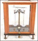 An early 20th Century wooden cased scientific scales in brass set to a black glass base with