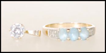 A hallmarked 9ct gold ladies dress ring set with three light blue stones with white accent stones to