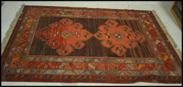 An early 20th Century Persian Islamic carpet floor rug having a central brown panel with two large