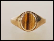 A 9ct gold ring set with an oval tigers eye panel to the head. Marks rubbed. Weight 3.8g. Size T.