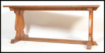An early 20th century golden oak refectory dining table. Raised on twin square column end supports
