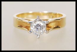 A stamped 18ct yellow gold ring having a decorative raised mount set with a single solitaire diamond
