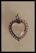 A hallmarked 9ct gold Edwardian locket pendant in the form of a heart having a glazed panel to the
