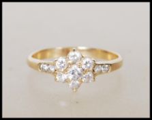 A stamped 585 14ct gold ring having a flower head set with seven white stones and accent stones to