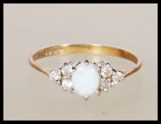 A hallmarked 9ct gold ring set with a opal cabochon flanked by six white accent stones. Hallmarked