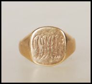 A 9ct gold signet ring having a cushion shaped panel head engraved with with initials. Assay marks