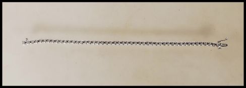 A hallmarked 9ct white gold bracelet having illusion set diamonds with a push button clasp. Approx