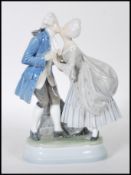 A Royal Copenhagen porcelain figurine depicting a Georgian couple kissing on a plinth base. Marks to