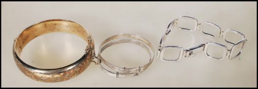 A group of marked silver bracelets to include a hallmarked bangle having a hinge clasp with safety