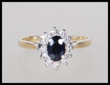 A hallmarked 9ct gold ring set with an oval cut sapphire with a halo of white stones. Hallmarked