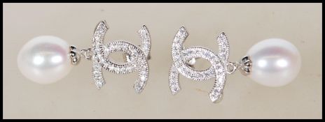 A pair of designer style silver and pearl drop earrings set with cz's. Gross weight 5.6g. Measures