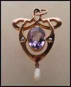 A stamped 9ct early 20th Century Art Nouveau pendant set with a large oval cut amethyst flanked by