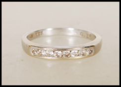 An 18ct English hallmarked white gold ring channel set with eight round cut diamonds. Hallmarked