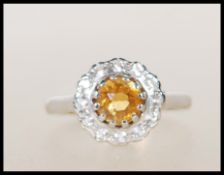 A hallmarked 9ct gold ring having central round cut orang stone surrounded by a halo of white stones