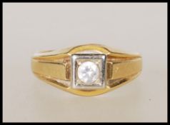 A stamped 750 18ct gold signet ring set with a round cut white stone within a white gold square head