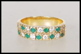 A stamped 18ct gold eternity ring set with two rows of alternate round cut diamond and emerald