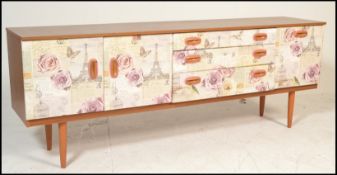 A mid 20th Century retro sideboard with a decoupage style front with fabric decorated cup handles.