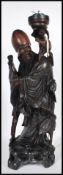 A 20th Century Chinese carved hardwood figure in the form of Shou-Lao bearing a scroll and raised on