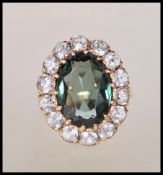 A stamped 9ct gold ring set with a oval cut green stone with a halo of white stones in a