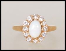 A hallmarked 9ct gold ring set with a central oval cabochon with a halo of white stones.