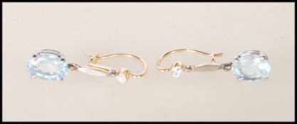 A pair of ladies gold drop earrings set with oval cut aquamarine stones with round cut diamonds