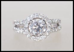 An 18ct white gold diamond ring having a central brilliant cut diamond with a halo of smaller stones