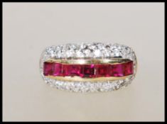 A stamped 9ct gold ladies dress ring set with a central row of square cut red stones surrounded by