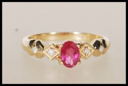 A hallmarked 9ct yellow gold ring having central oval faceted cut pink stone flanked by white accent