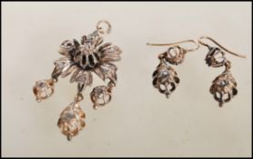 A 19th Century floral diamond and white metal pendant and earrings demi parure set, the pendant in