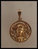 An 18ct gold unmarked Madonna pendant having to include a round pendant with pierced decoration.