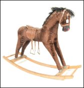 A 1960s rocking horse with brown plush hair and a painted wooden muzzle saddle and stirrups raised