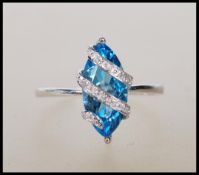 A hallmarked 9ct white gold ring having prong set lozenge shape blue stone with overlapping illusion