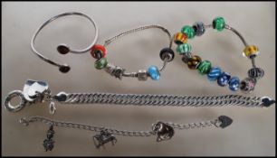 A selection of silver bracelets to include two snake chain bracelets having beaded charms, a cuff