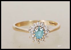 A 9ct gold English hallmarked ring set with a central blue oval cut stone having a halo of white