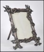 A silver white metal picture frame molded in the form of textured tree trunks with branch accents.